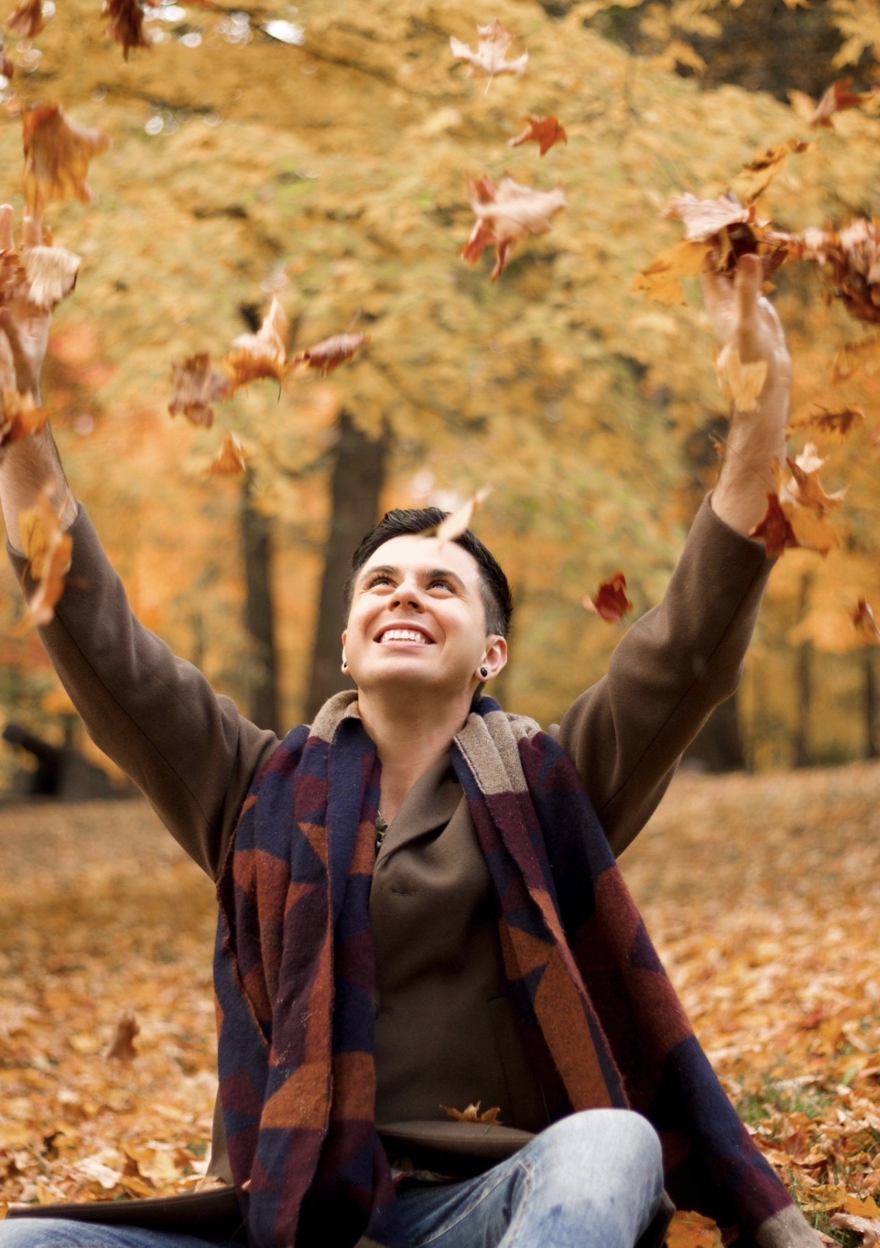 Alex sourit en lançant des feuilles d’automne dans les airs
